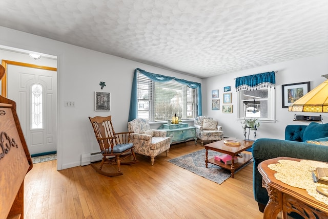 sitting room featuring a textured ceiling, baseboard heating, wood-type flooring, and baseboards