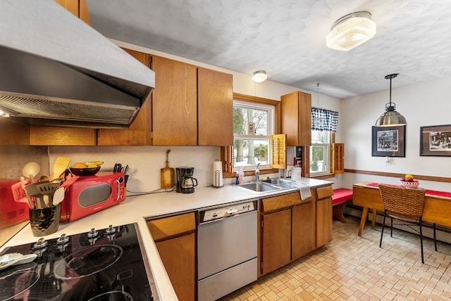 kitchen with brown cabinetry, decorative light fixtures, range hood, white dishwasher, and light countertops