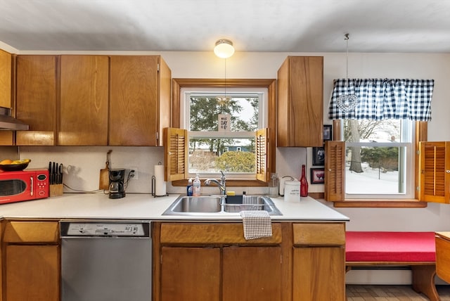 kitchen with dishwashing machine, brown cabinetry, a sink, and light countertops