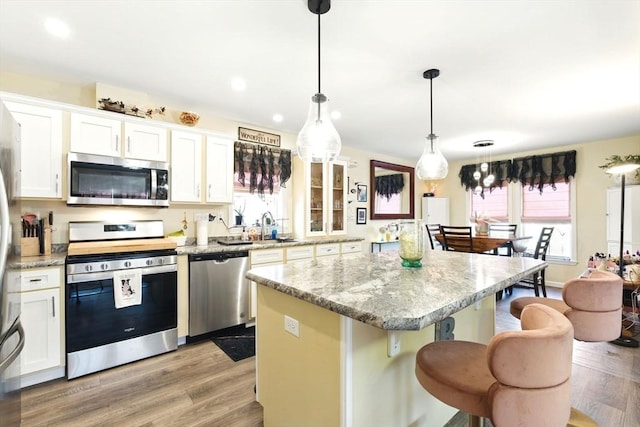 kitchen featuring a breakfast bar area, light wood finished floors, a kitchen island, stainless steel appliances, and white cabinetry