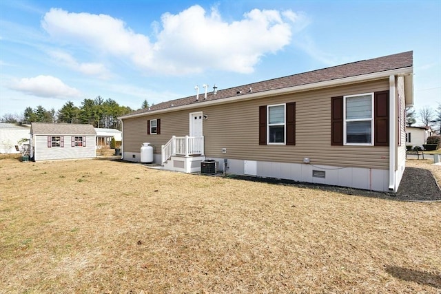 rear view of house featuring crawl space, a lawn, central AC, and an outdoor structure