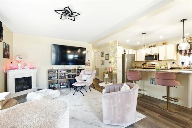 living area with a glass covered fireplace, recessed lighting, dark wood-type flooring, and baseboards