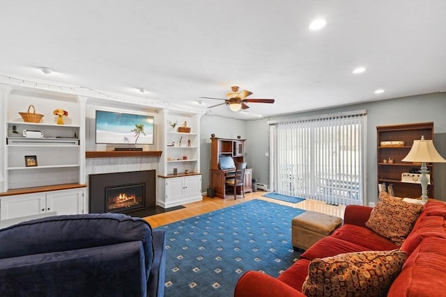 living room with ceiling fan, a baseboard radiator, built in shelves, and light hardwood / wood-style floors