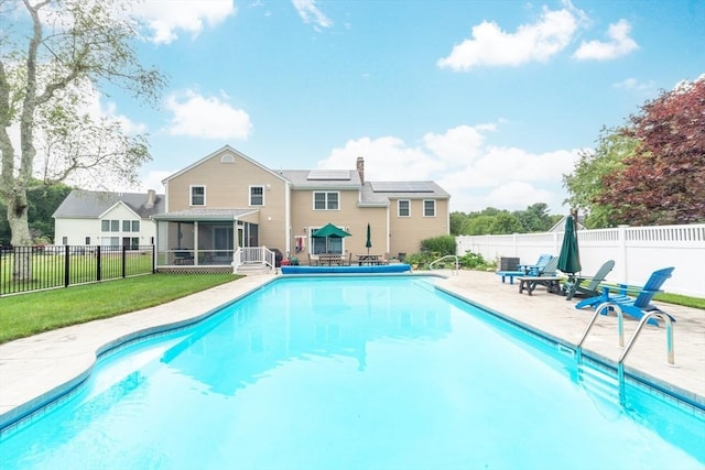 view of swimming pool with a sunroom, a lawn, and a patio area