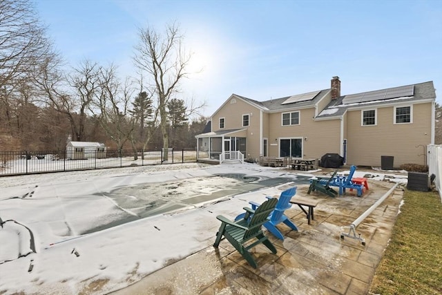 rear view of house with a covered pool, a sunroom, a patio, and solar panels