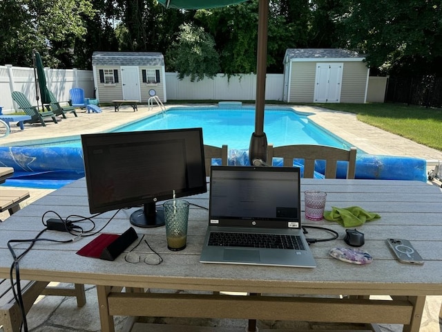 view of pool featuring an outdoor fire pit, a patio area, and a shed