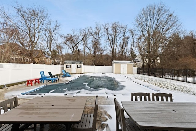 snowy yard with a storage shed and a covered pool