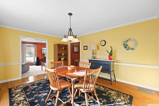 dining area featuring crown molding and light hardwood / wood-style flooring