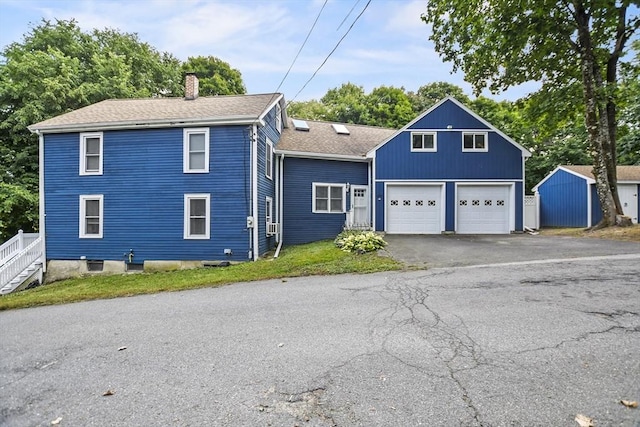 view of front of property featuring driveway, a chimney, a garage, and a shingled roof