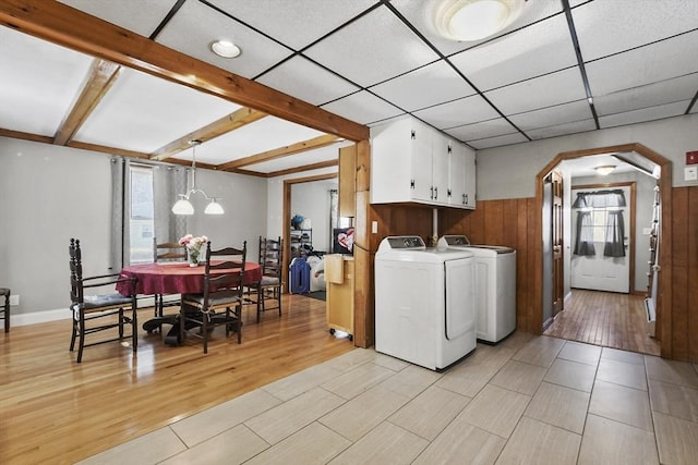 laundry room featuring light wood-style flooring, cabinet space, a healthy amount of sunlight, and washing machine and dryer