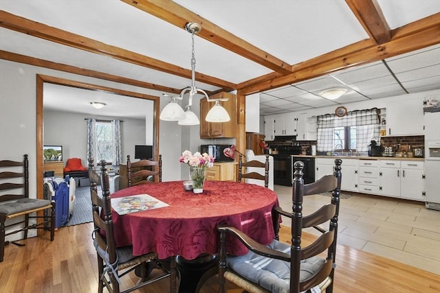 dining room featuring beamed ceiling and light wood-type flooring