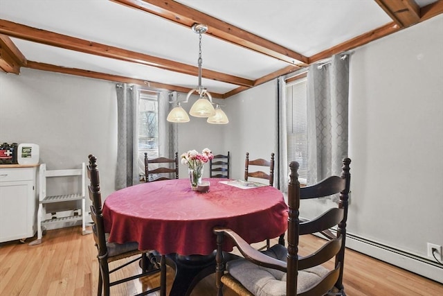 dining area featuring a baseboard heating unit, beam ceiling, and light wood-style flooring