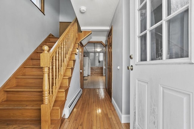 stairs with baseboard heating, baseboards, and hardwood / wood-style flooring