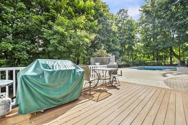 deck with an outdoor pool, outdoor dining area, area for grilling, and fence