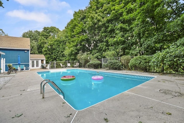 view of pool with an outbuilding, fence, french doors, a fenced in pool, and a patio area