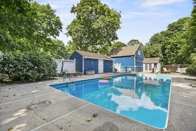 view of pool with a fenced in pool, a patio, an outbuilding, and fence