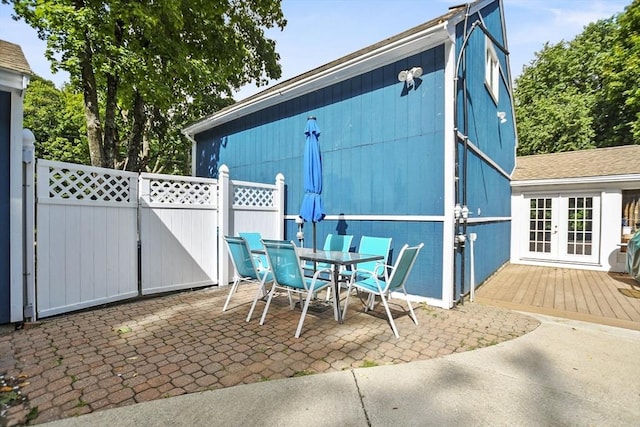 view of patio featuring a gate, outdoor dining space, french doors, and fence