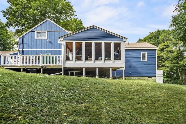 back of property with a lawn, a deck, and a sunroom