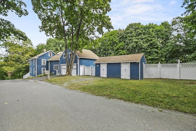 view of front facade with a storage unit, an outdoor structure, a front yard, and fence