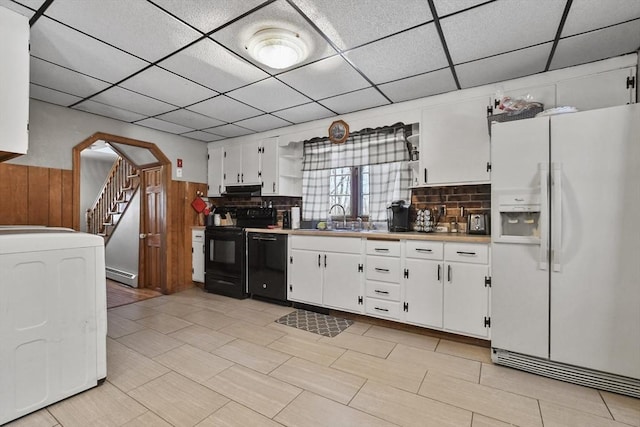 kitchen featuring black appliances, under cabinet range hood, a baseboard heating unit, washer / clothes dryer, and arched walkways