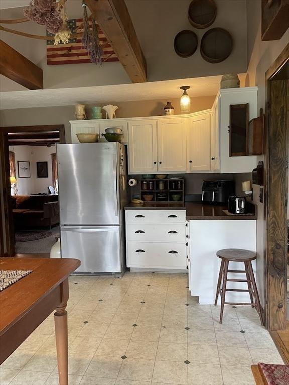 33 Whittemore St, Leicester, MA 01524 - kitchen featuring freestanding refrigerator, beamed ceiling, dark countertops, and white cabinets