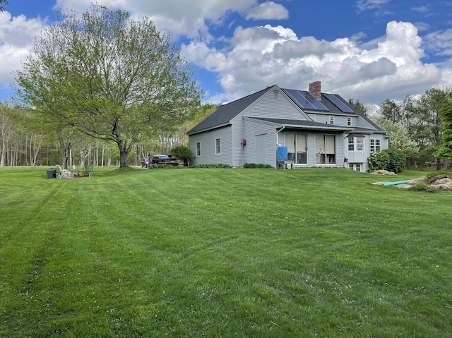 33 Whittemore St, Leicester, MA 01524 - back of house with roof mounted solar panels, a chimney, and a yard