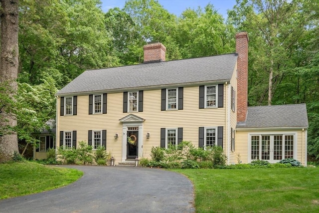 153 Old Connecticut Path, Wayland, MA 01778 - colonial-style house featuring a chimney, a front yard, asphalt driveway, and a shingled roof