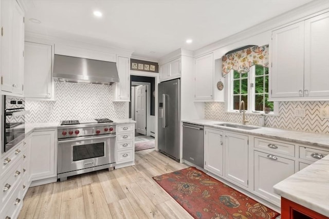 153 Old Connecticut Path, Wayland, MA 01778 - kitchen featuring high end appliances, wall chimney exhaust hood, white cabinets, light wood-type flooring, and decorative backsplash