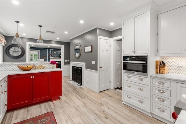 153 Old Connecticut Path, Wayland, MA 01778 - kitchen featuring stainless steel oven, wainscoting, white cabinets, crown molding, and light wood-type flooring