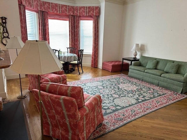 living area with baseboards, wood finished floors, and crown molding