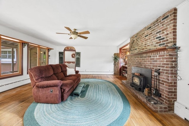 148 Walnut Hill Rd, Orange, MA 01364 - living area with wood finished floors, ceiling fan, a baseboard radiator, and a wood stove
