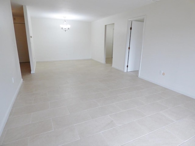 tiled empty room featuring a notable chandelier