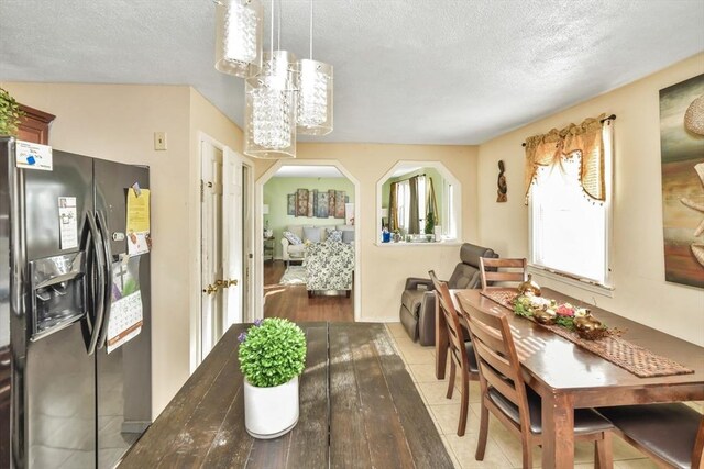 dining area with tile patterned flooring, arched walkways, and a textured ceiling