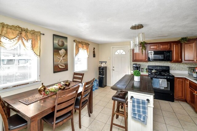 kitchen with black appliances, light tile patterned floors, and a wealth of natural light