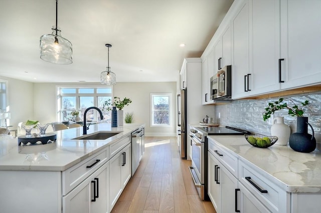 62 Foundry St Unit 215, Wakefield, MA 01880 - kitchen featuring appliances with stainless steel finishes, a large island with sink, backsplash, white cabinetry, and light wood-style flooring