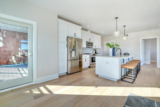 62 Foundry St Unit 215, Wakefield, MA 01880 - kitchen with stainless steel appliances, a kitchen bar, light wood finished floors, white cabinetry, and an island with sink