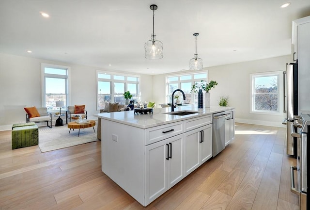 62 Foundry St Unit 215, Wakefield, MA 01880 - kitchen featuring stainless steel dishwasher, open floor plan, light wood-style flooring, a kitchen island with sink, and recessed lighting