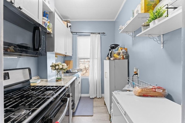 kitchen featuring white cabinets, ornamental molding, and stainless steel gas range