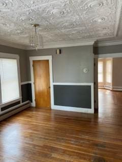 10 Stevens St, Lawrence, MA 01843 - empty room featuring a chandelier, crown molding, a baseboard heating unit, and wood finished floors