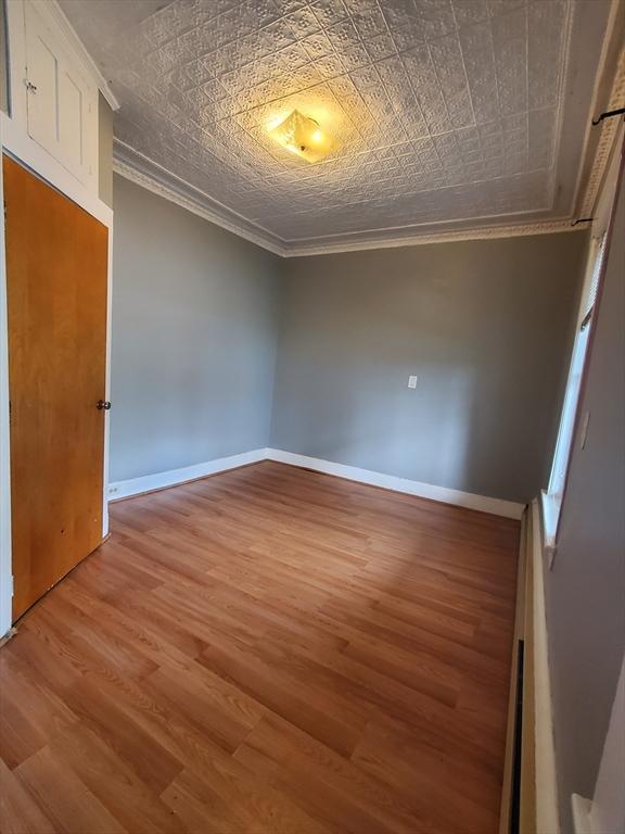 10 Stevens St, Lawrence, MA 01843 - spare room with crown molding, light wood-type flooring, an ornate ceiling, and baseboards