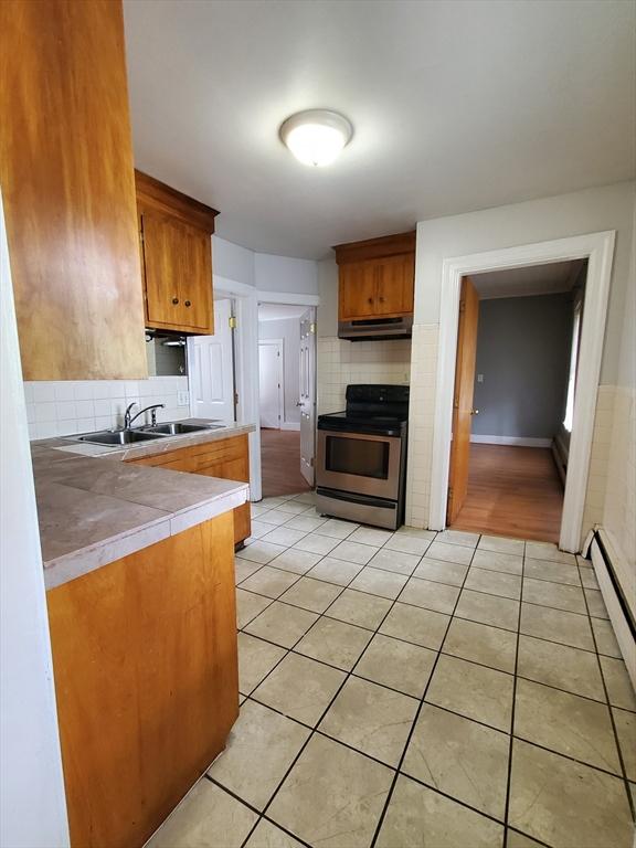 10 Stevens St, Lawrence, MA 01843 - kitchen featuring electric range, under cabinet range hood, a sink, light tile patterned floors, and backsplash