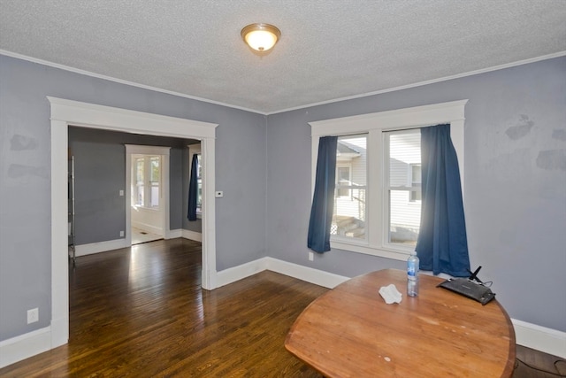 unfurnished dining area featuring dark wood-type flooring, a textured ceiling, and ornamental molding