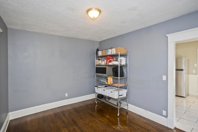 home office with light hardwood / wood-style floors and a textured ceiling