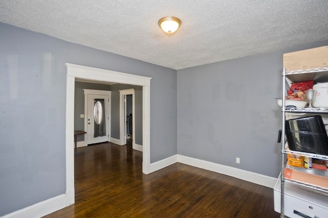 empty room with a textured ceiling and dark hardwood / wood-style floors