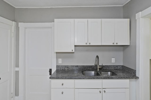 kitchen featuring white cabinetry, sink, dark stone counters, and a textured ceiling