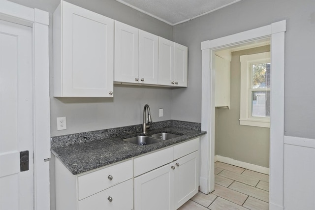 kitchen with white cabinets, dark stone countertops, sink, and a textured ceiling