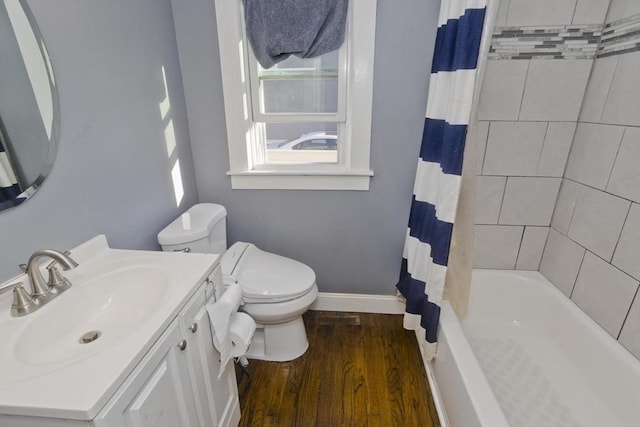 full bath with toilet, wood finished floors, vanity, baseboards, and shower / bath combo