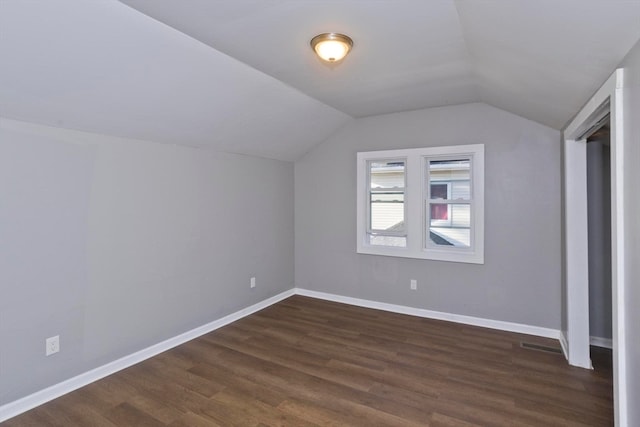 additional living space featuring dark wood-type flooring and vaulted ceiling