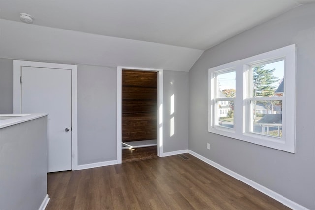 unfurnished bedroom with dark hardwood / wood-style flooring and vaulted ceiling