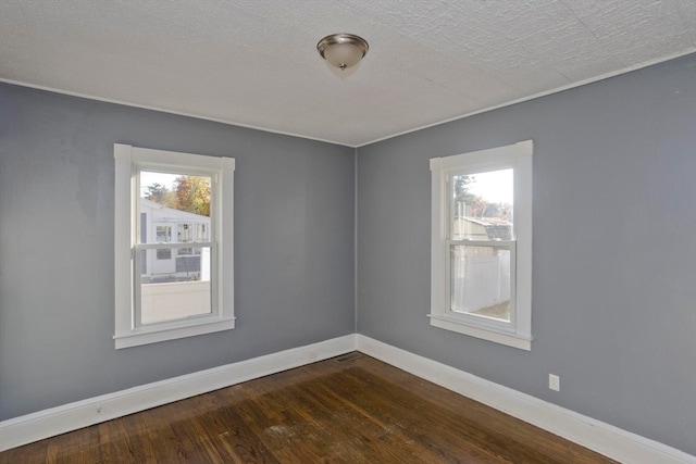 empty room featuring dark wood-type flooring and a textured ceiling